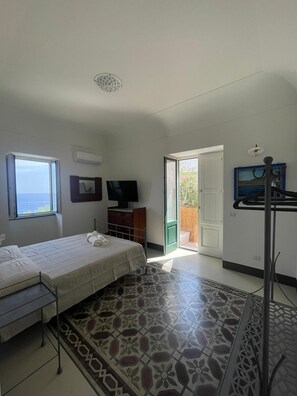 Ein Schlafzimmer mit Bett, Fernseher, Kleiderschrank, Fenster mit Aussicht und einem gemusterten Boden.
