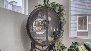 Et værelse med et stort rundt spejl på et stativ, en sofa og en potteplante.