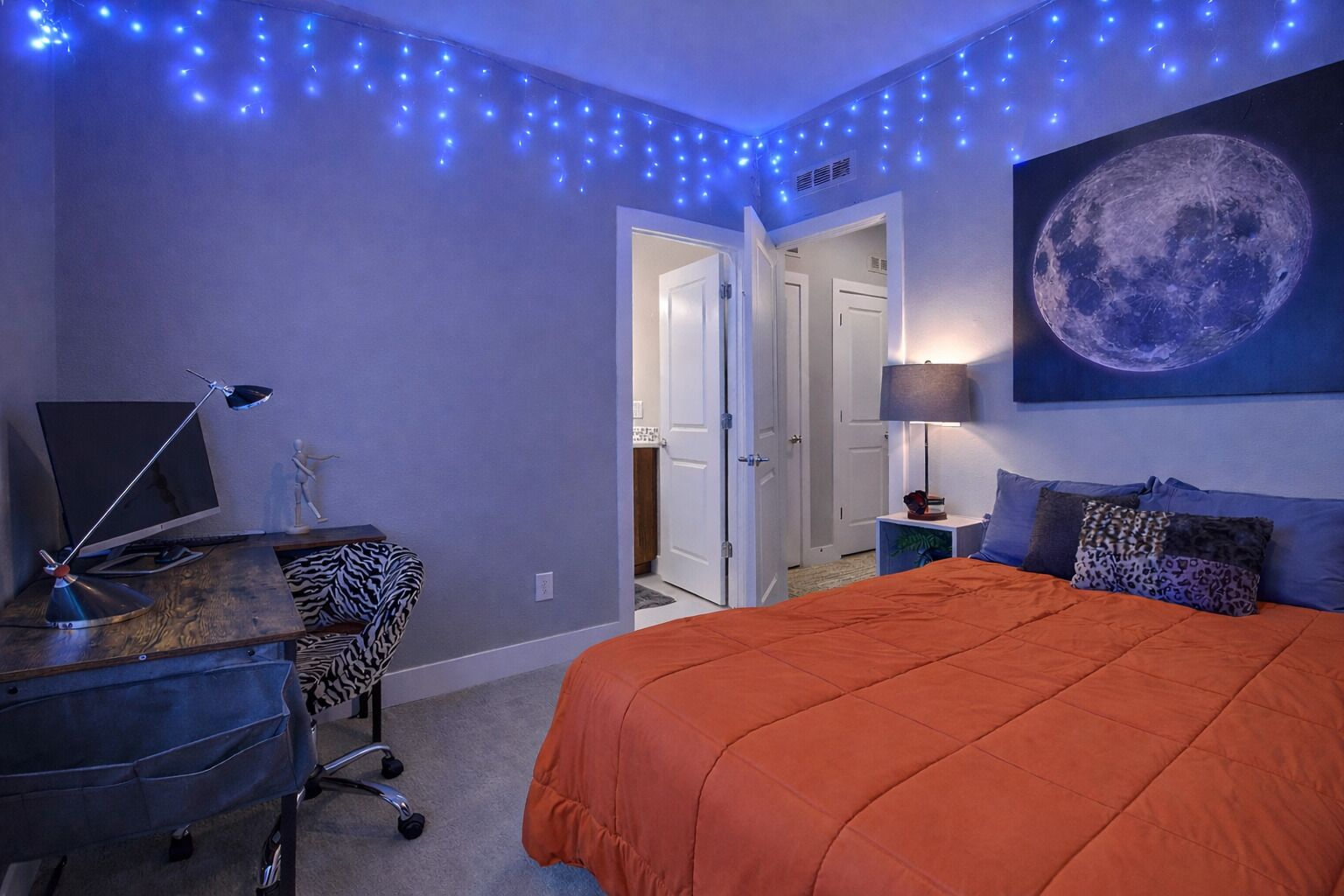 Une chambre à coucher comprenant un lit, un bureau, une chaise et un téléviseur fixé au mur.