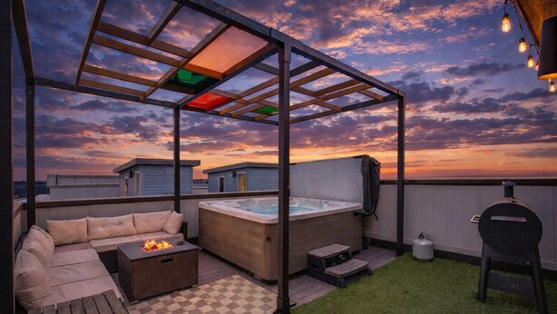 En tagterrasse med jacuzzi, siddepladser og grill.