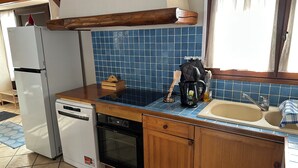 A compact kitchen with a white refrigerator, a dishwasher, a wooden countertop, a blue-tiled backsplash, and a window with curtains. - Charming family gîte "Le Nid de Chartreuse" in Saint Christophe la Grotte (Saint-Christophe)