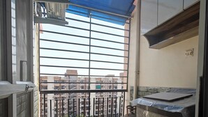 A balcony with a view of buildings, a gas cylinder, and a water heater. - Casa InteliStay – Smart, Stylish 2BHK in Lucknow (Lucknow)
