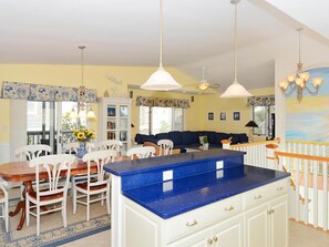 A kitchen with a blue countertop, white cabinets, and a dining area with a wooden table and chairs. - 4BR House w/ Deck | Close to Beach! (South Bethany Beach)
