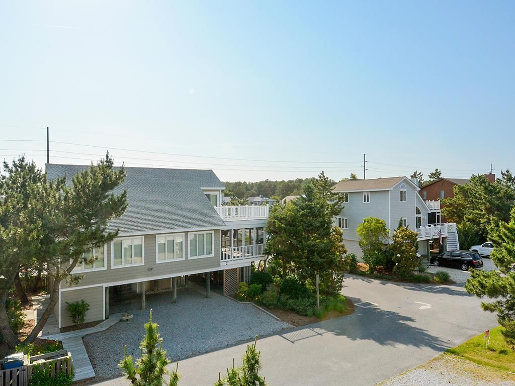 Un quartier résidentiel avec une maison à deux étages dotée d’un patio couvert et d’un garage séparé.