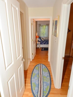 A hallway with a wooden floor leading to a bedroom with a bed and a window. - 4BR House w/ Deck | Close to Beach! (South Bethany Beach)