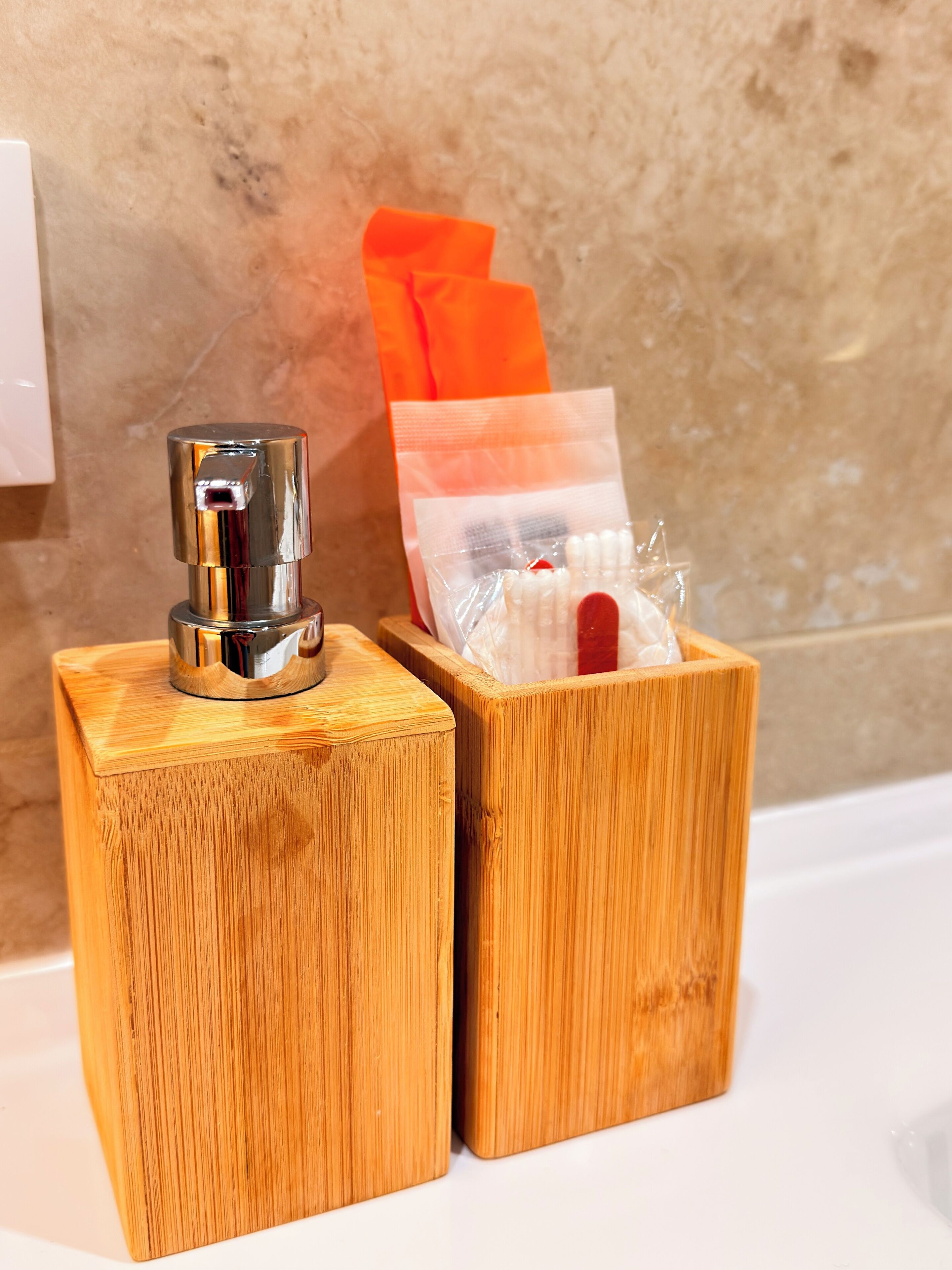 Two wooden boxes with a metallic object on top, a plastic bag with white items, and an orange cloth on a white surface.