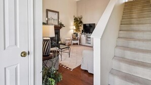 A spacious living area with a staircase, a fireplace, and a television. - 3BR House near Bethany Beach | Pool Access (Frankford)