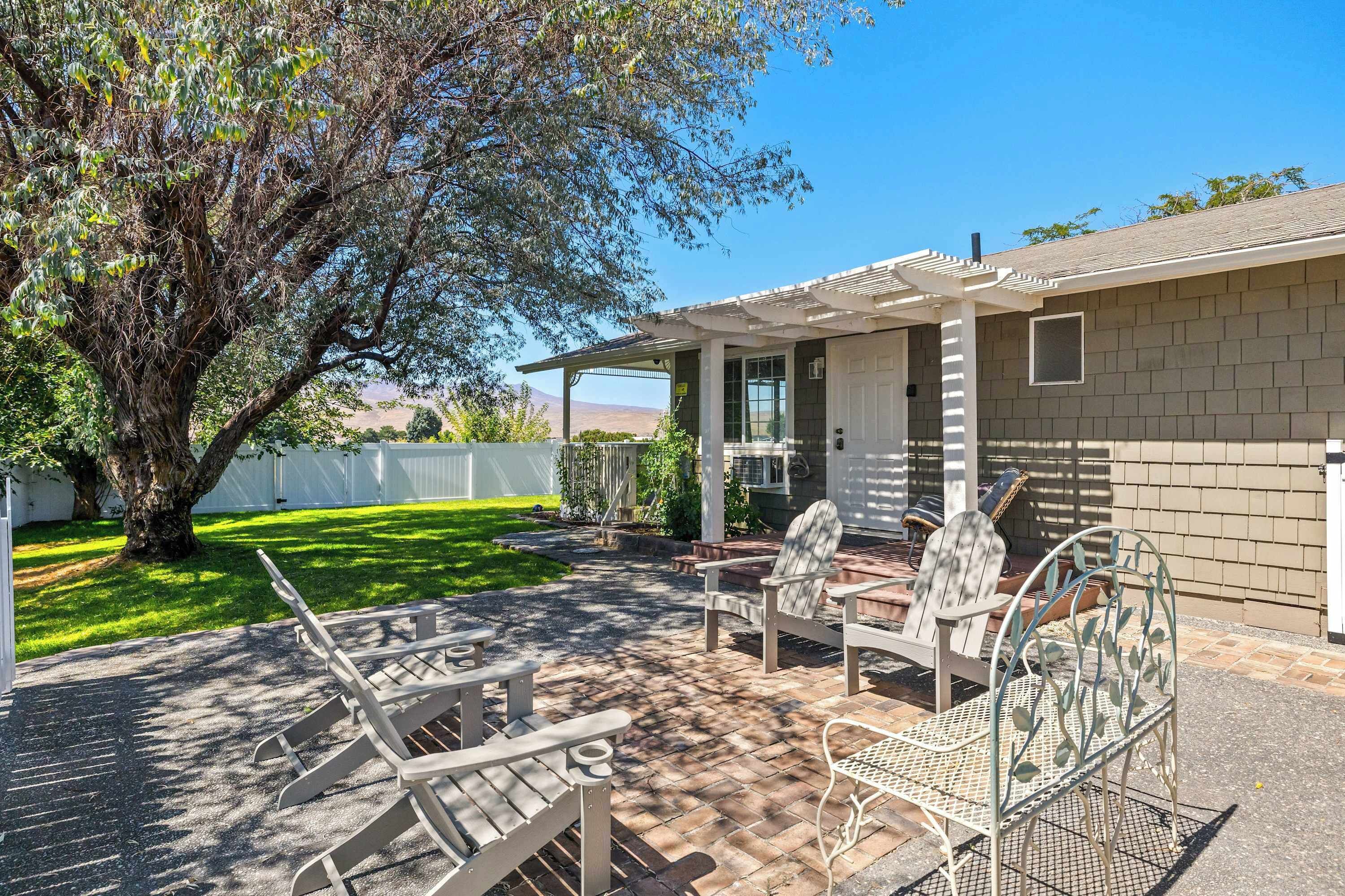 A patio with outdoor furniture, a covered seating area, and a view of a house with a brick exterior.