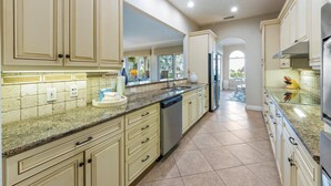 A spacious kitchen with light-colored cabinetry, a granite countertop, and stainless steel appliances. - Direct Beach Access Beautiful Resort Balcony (Holmes Beach)