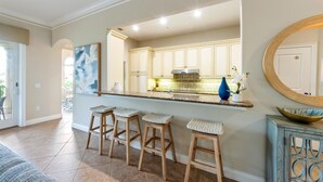 A kitchen with a bar area, wooden stools, and a large mirror. - Direct Beach Access Beautiful Resort Balcony (Holmes Beach)