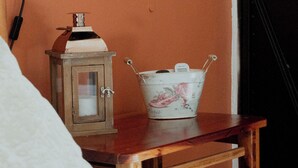 Ein Schlafzimmer mit Nachttisch aus Holz, einem weißen Bett, einer Lampe, einem Laternen und einem dekorativen Eimer.