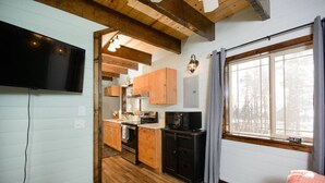 A compact kitchen with wooden cabinets, a microwave, and a stove. - Charming 2-bedroom cottage in Homer perfect for relaxing stays. (Homer)