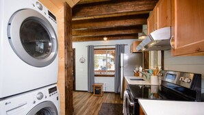 A compact kitchen with a washing machine, a refrigerator, and a stove. - Charming 2-bedroom cottage in Homer perfect for relaxing stays. (Homer)
