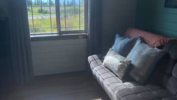 Una habitación con sofá, ventana con cortinas y vista a un paisaje.