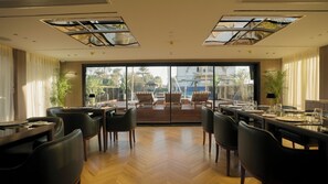 Un restaurante con vistas al mar, suelo de madera y mobiliario moderno.