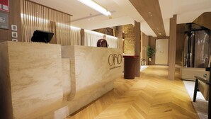 A reception desk with a wooden finish and the logo 'Oro Luxury Mile Experience'.