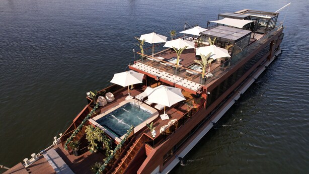 A large river cruise ship with a swimming pool, sun loungers, and umbrellas.
