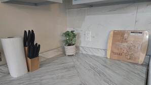 Eine Küche mit Marmorarbeitsplatten, einem Messerblock, Küchenpapier und einem Blumentopf, sowie einer Karte von Texas.