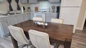 Eine Küche mit einem Holztisch, weißen Stühlen und einer Schale mit dekorativen Kugeln.