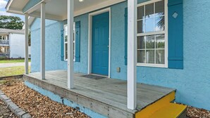 Una casa con fachada azul, un porche de madera y una puerta azul.