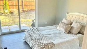 Ein Schlafzimmer mit einem Bett, einem Deckenventilator und einer Glastür, die in einen Garten führt.