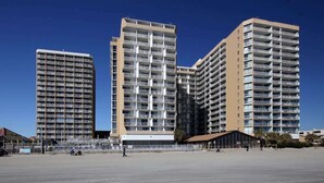 Three high-rise buildings with multiple balconies, a flat rooftop area, and a clear sky. - Carol's Coastal Getaway (Myrtle Beach)