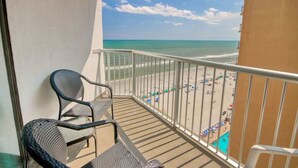 A balcony with a view of the beach, featuring a metal railing and two wicker chairs. - Carol's Coastal Getaway (Myrtle Beach)