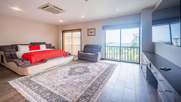 A modern bedroom with a large bed, a sofa, a chair, and a balcony with a city view. - 5 Bedroom Penthouse Ocean Views Jacobay 21002 (Jaco)