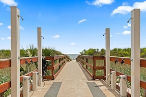 A wooden boardwalk leading to a beach with water jets on either side. - "The Salty Compass" 3 BR Ocean Front in Windy Hill (North Myrtle Beach)