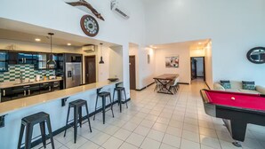 A spacious living area with a kitchen, dining table, and a pool table. - 7 Bedroom Penthouse Ocean & Mountain Views JB31002 (Jaco)