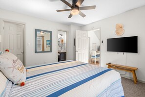 Un dormitorio con cama, ventilador de techo, televisión y banca.