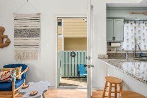 A modern kitchen with a granite countertop, a wooden stool, and a blue chair. - Anchors Away Two Blocks to Surfside Beach. (Surfside Beach)
