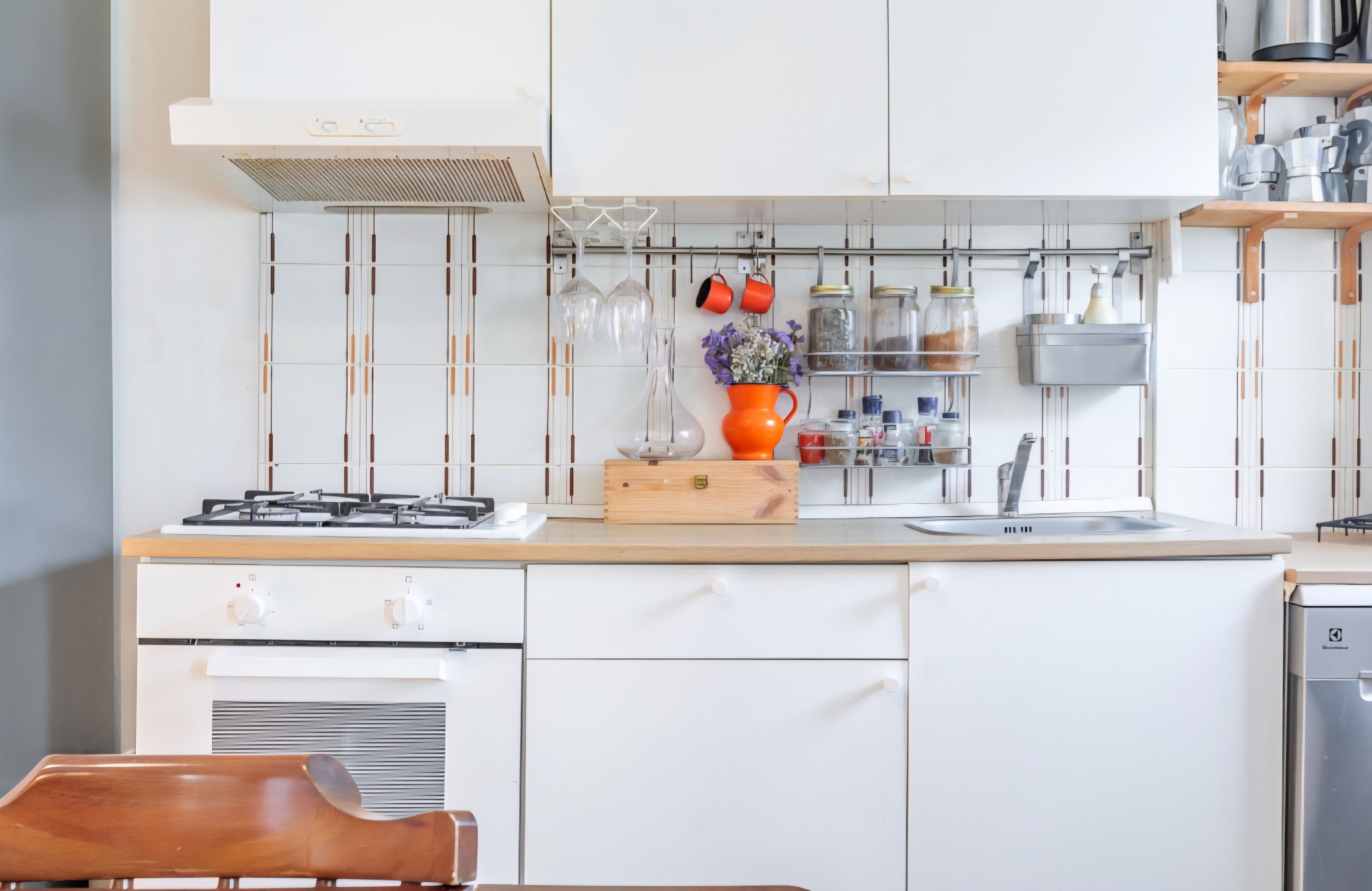 A modern kitchen with white cabinets, a gas stove, a wooden countertop, and a built-in oven.
