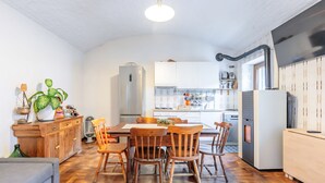 A compact kitchen with white cabinets, a dining table with wooden chairs, a built-in oven, and a large window. - Casa Olinda, which opens to Mount Emilius and the Gran Paradiso massif. (Saint-Christopher)