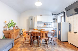 A compact kitchen with white cabinets, a dining table with wooden chairs, a built-in oven, and a large window. - Casa Olinda, which opens to Mount Emilius and the Gran Paradiso massif. (Saint-Christopher)