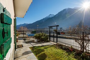 Une terrasse avec vue sur les montagnes, une piscine et un espace clos agrémenté de plantes en pot.
