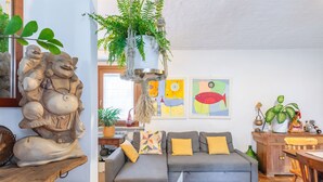 A living room with a grey sofa, a wooden coffee table, and a hanging plant. - Casa Olinda, which opens to Mount Emilius and the Gran Paradiso massif. (Saint-Christopher)