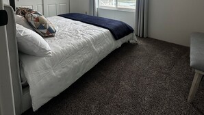 Ein Schlafzimmer mit Bett, Fenster mit Meerblick, Deckenleuchte und Tür.