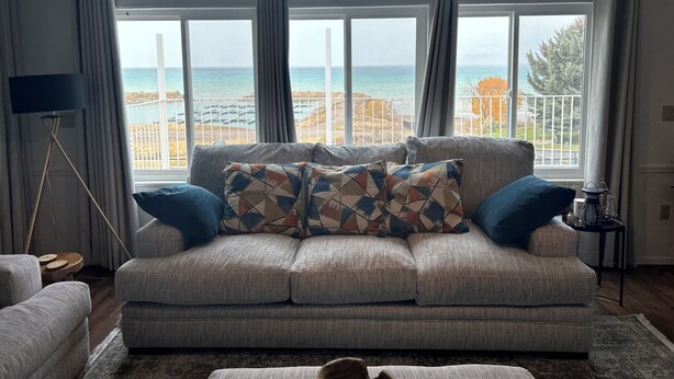 Ein Wohnzimmer mit einer Couch, einer Stehlampe und Blick auf den Ozean.