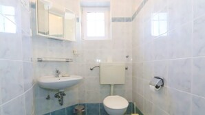 Une salle de bain avec un lavabo, des toilettes et un miroir, le tout de couleur blanche.