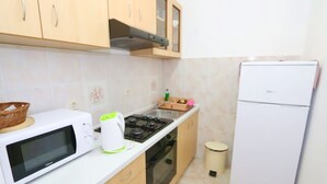 Uma cozinha compacta com micro-ondas, chaleira, fogão e geladeira.