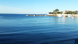 Vista costeira com mar calmo, um cais e edifícios ao fundo.