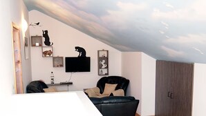 Una sala de estar moderna con techo inclinado, televisor de pantalla plana, sofá de cuero negro y armario de madera.