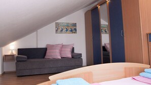 Un dormitorio moderno con un sofá gris, una cama de madera y un espejo grande.