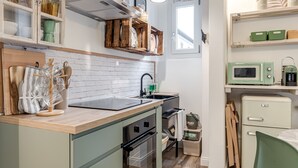 Uma cozinha compacta com bancada de madeira, pia, micro-ondas e geladeira.