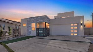 Una casa moderna con garaje, entrada para vehículos y un pequeño jardín.