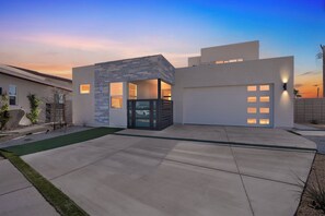 A modern house with a garage, a driveway, and a small garden area. - Casa Volare- Pool+Spa, Gated 4BR 3BA 2,400sqft Brand New Desert Retreat (Bermuda Dunes)