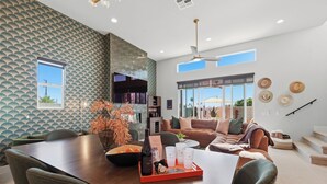 Una sala de estar moderna con comedor, ventanas amplias y un papel tapiz estampado.