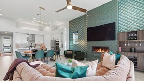 Una sala de estar moderna con chimenea, comedor y cocina.