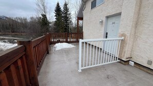 A wooden deck with a white metal gate, a concrete floor, and a building with a door marked "641". - 1BR Suite with River & Mountain Views in Fernie (Fernie)